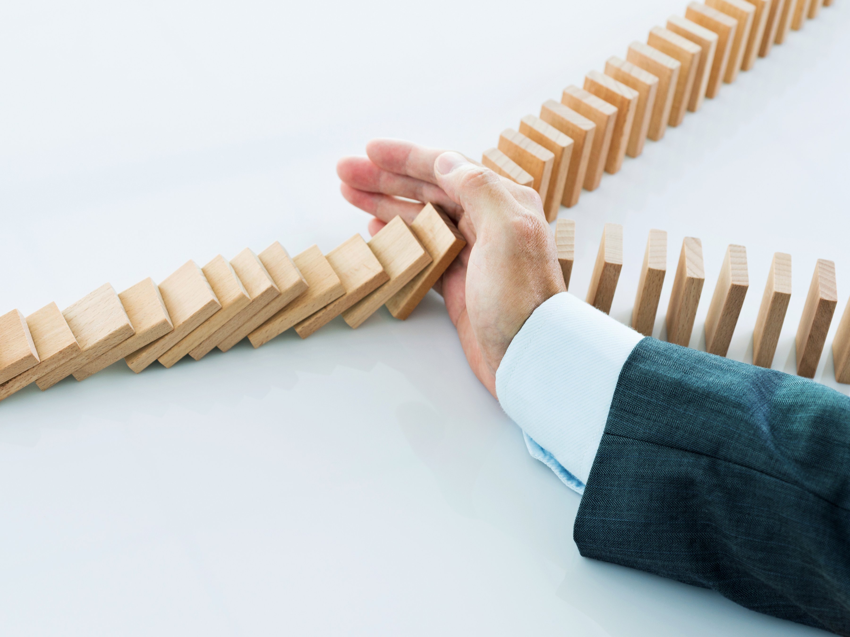 Business Man Stopping Falling Dominoes